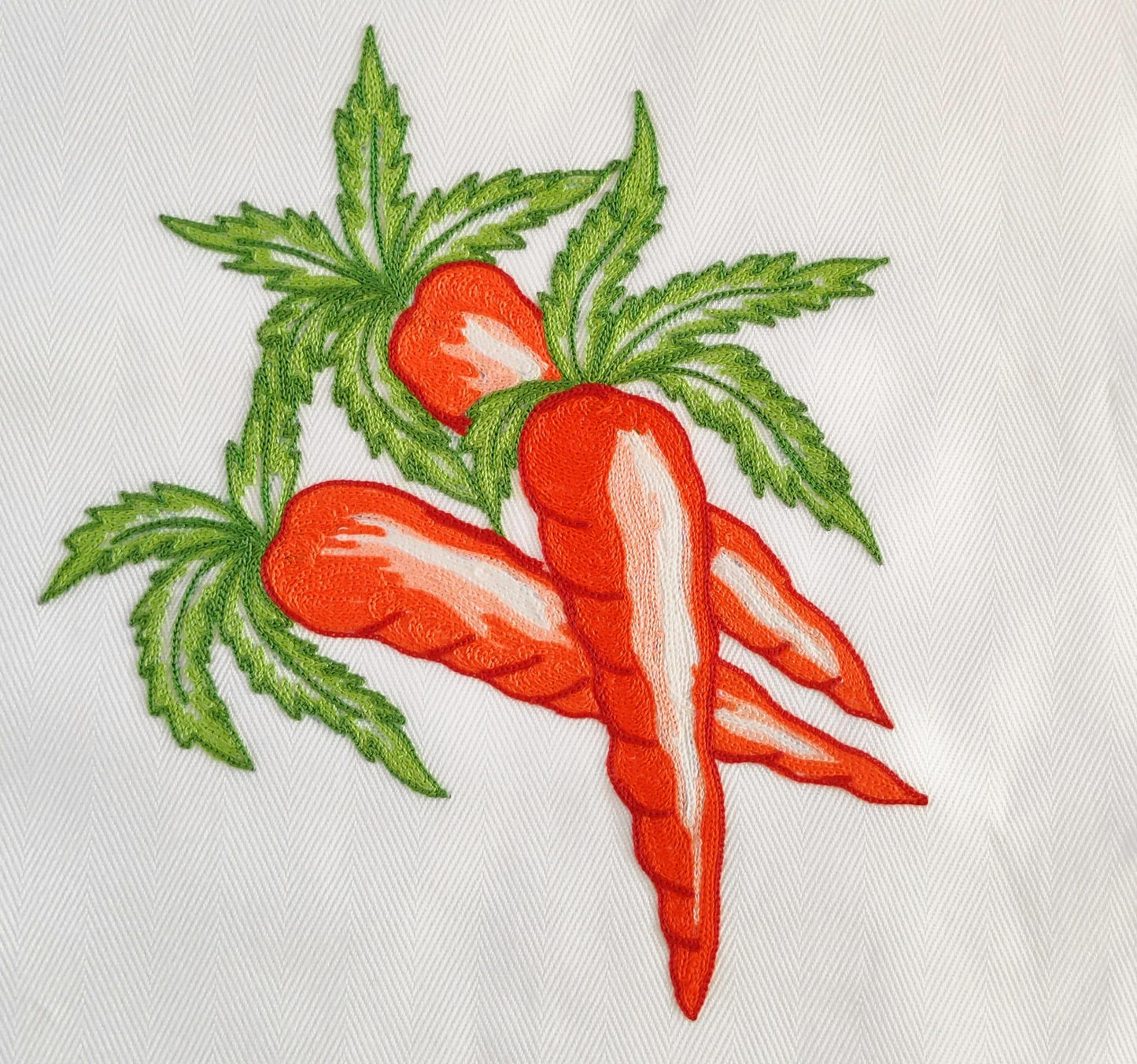 Particolare ricamo a mano carote con foglie su cotone bianco Made in Italy