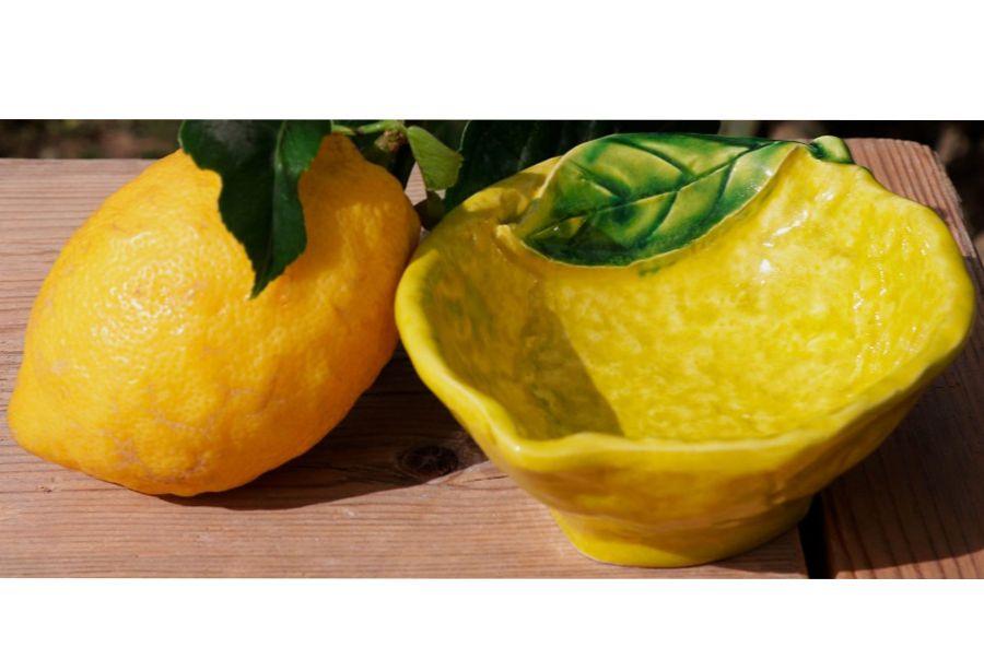 Coppetta in ceramica a forma di limone Ø16 cm accanto a limone fresco – Linea Agrumi Virginia Casa, artigianato toscano.