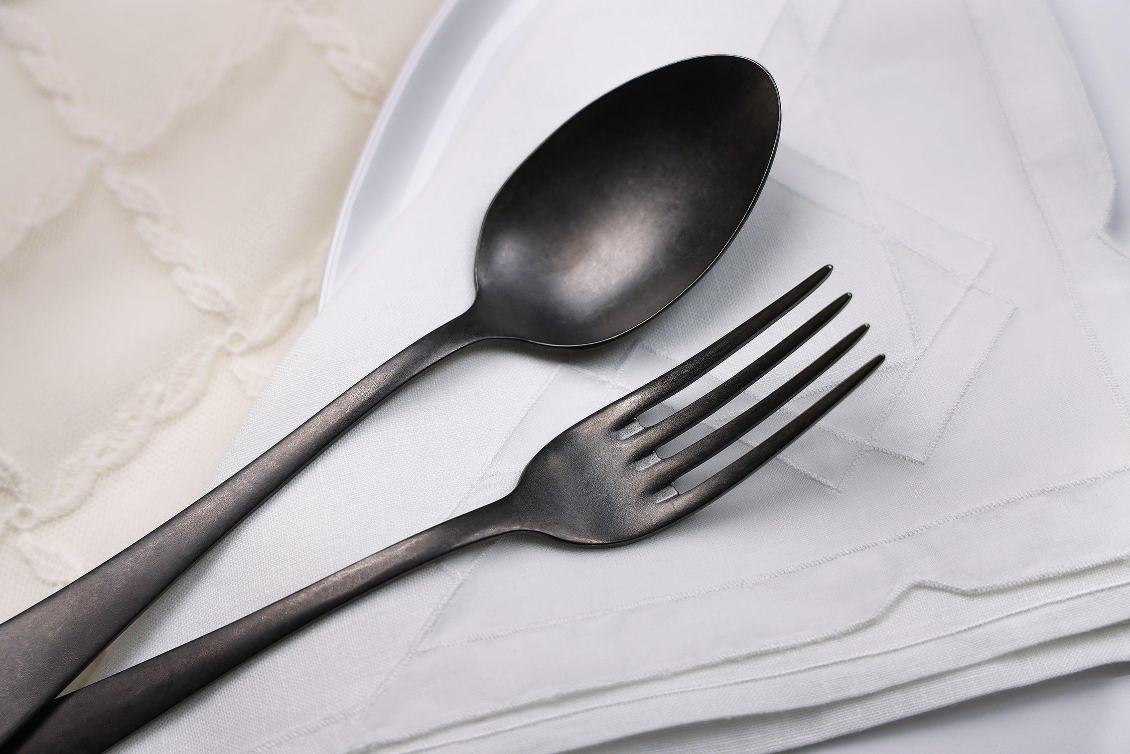 Posate in metallo scuro su tovagliolo bianco – design elegante per la tavola