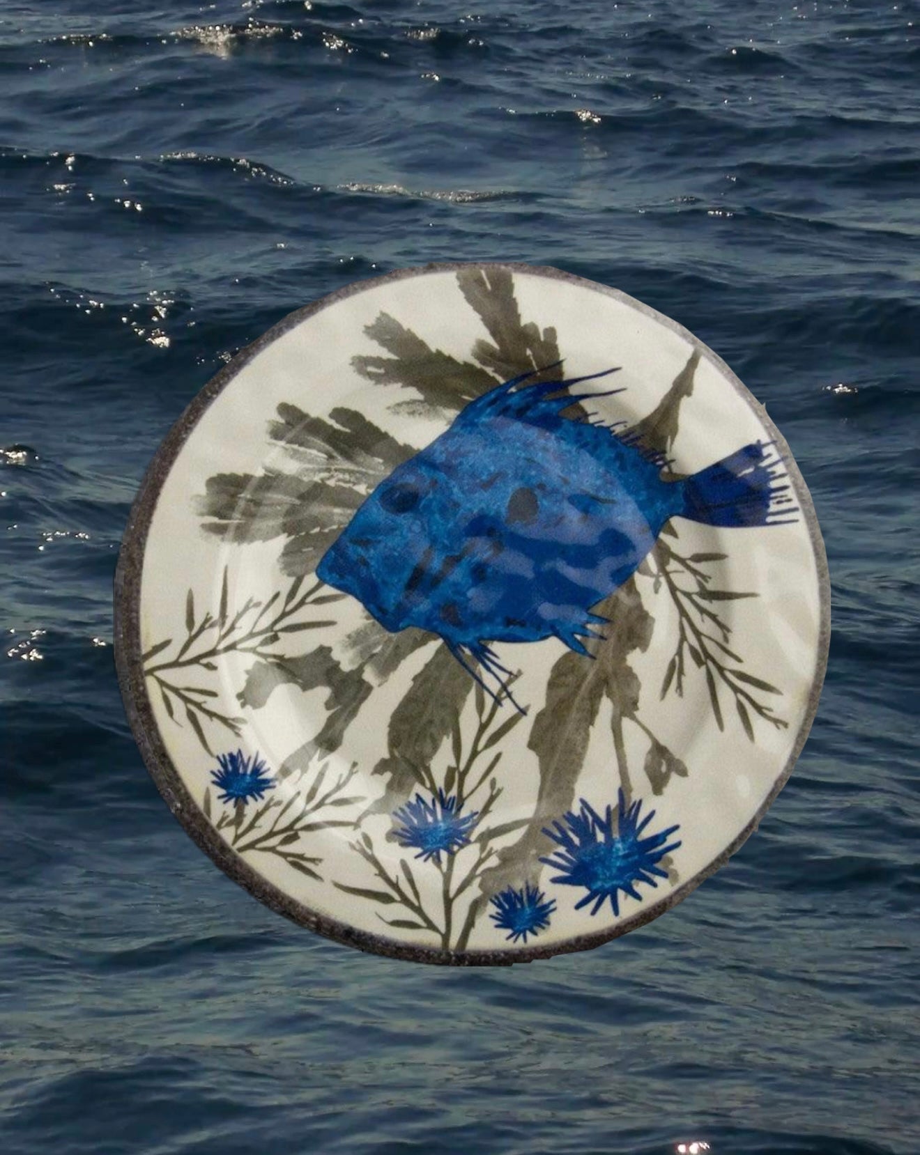 Piatto piano in melanina con motivo marino blu raffigurante un San Pietro e ricci fotografato su sfondo acqua