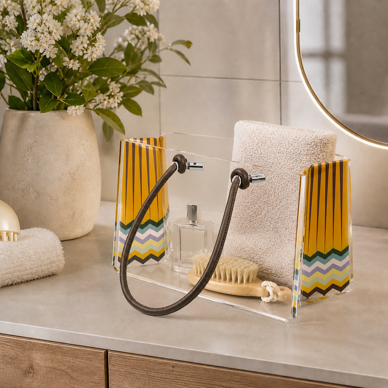 Contenitore Charlotte Piccola Rainbow Vesta Home in plexiglass trasparente con manici in ecopelle, utilizzato come organizer bagno con asciugamano e accessori su piano moderno
