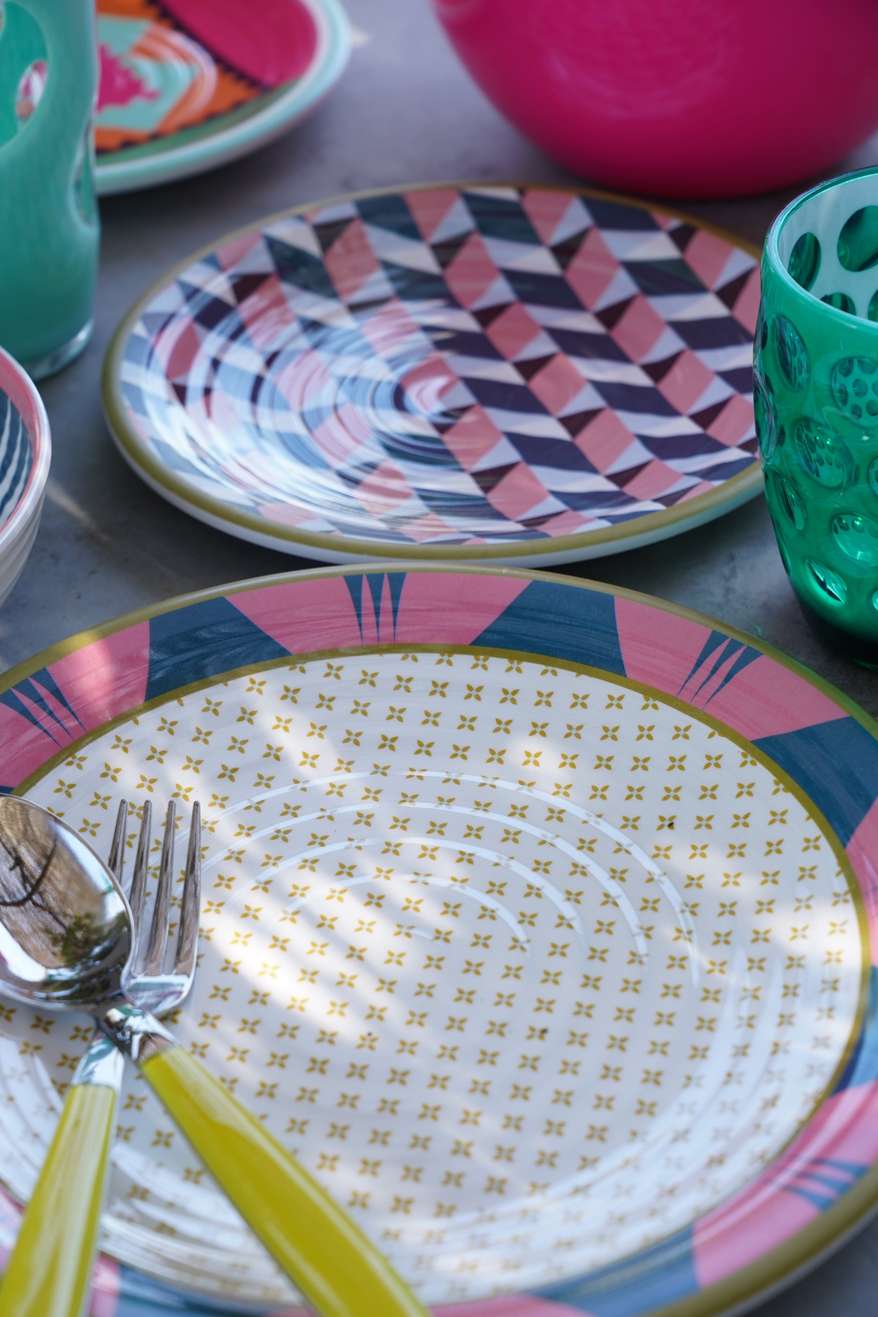 Piatti Modern Vesta in melamina con design geometrico multicolor, set da tavola apparecchiato con posate e bicchieri colorati