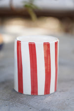 Bicchiere in ceramica artigianale a righe rosse e bianche su superficie in pietra