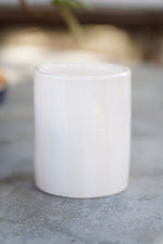 Bicchiere in ceramica artigianale crema bianco lucido su superficie in pietra all’aperto