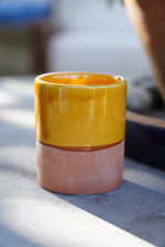 Tazzina in ceramica artigianale gialla con base in terracotta su tavolo all’aperto