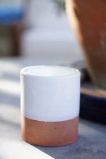 Tazzina in ceramica artigianale bianca con base in terracotta su tavolo all’aperto