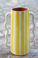 Vaso caraffa artigianale in ceramica a righe gialle e bianche, altezza 28 cm, fatto a mano, appoggiato su tavolo in legno all’aperto