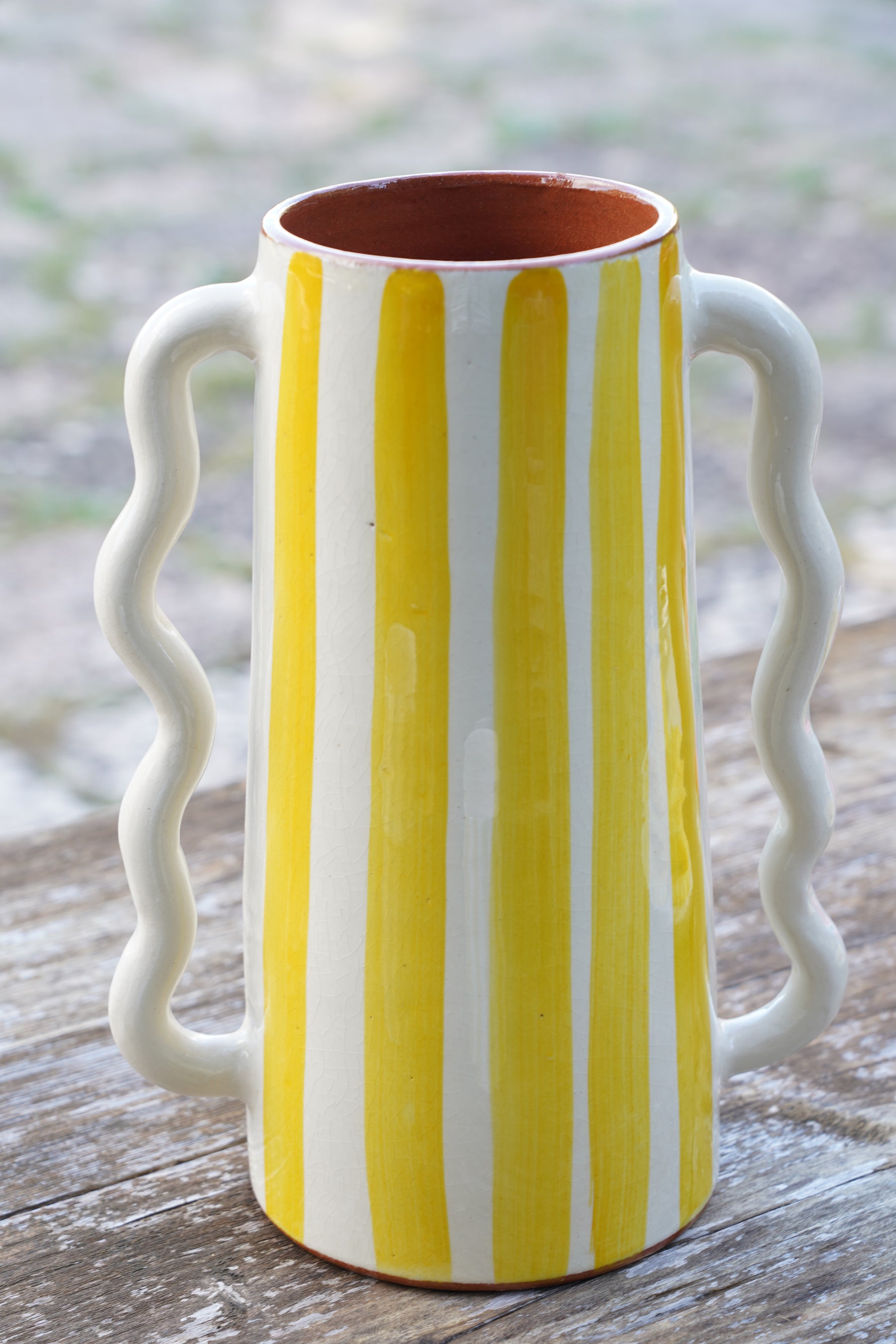 Vaso caraffa artigianale in ceramica a righe gialle e bianche, altezza 28 cm, fatto a mano, appoggiato su tavolo in legno all’aperto