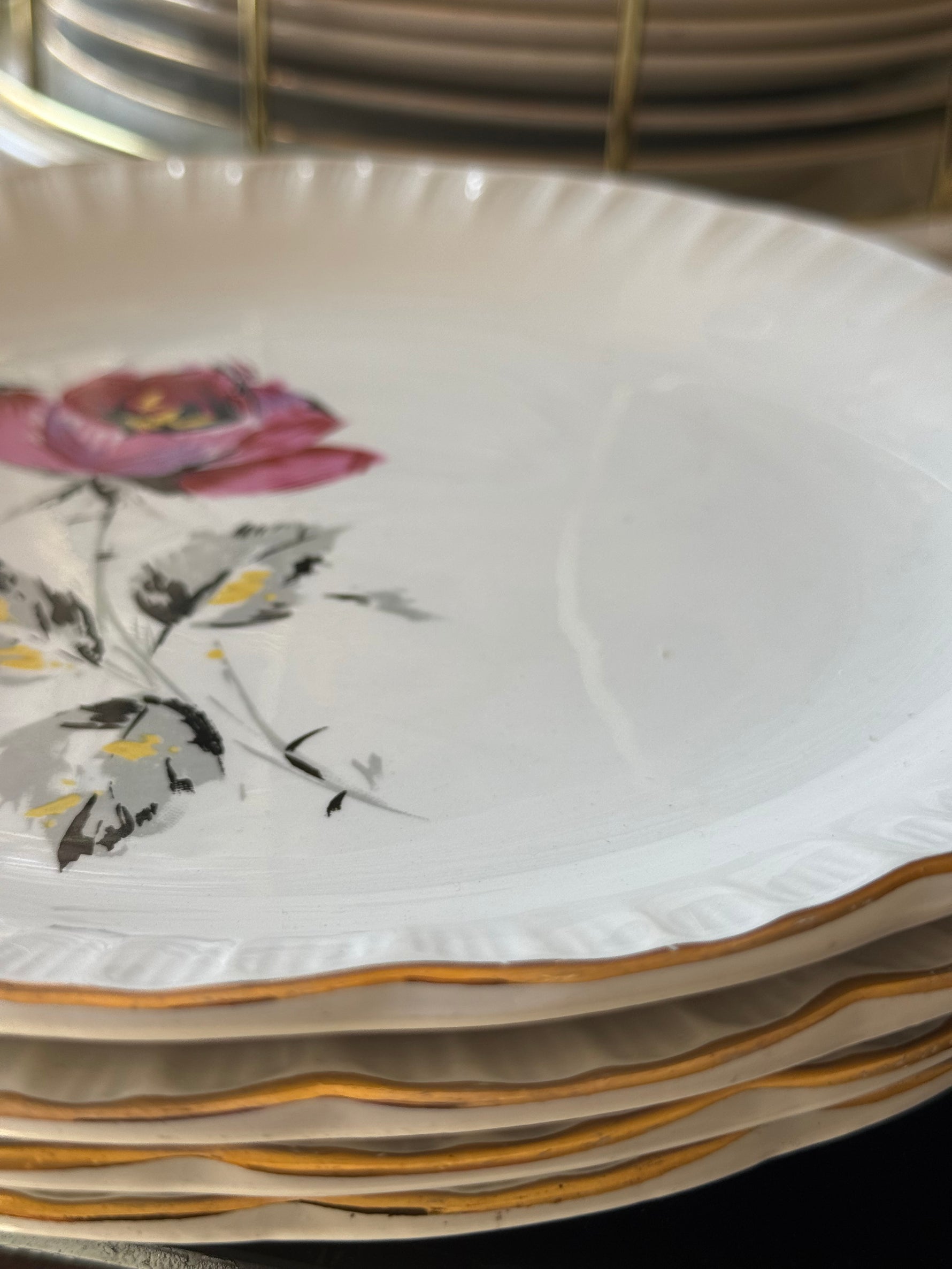 Dettaglio piatti vintage francesi in ceramica con bordo dorato ondulato e decoro floreale rosa