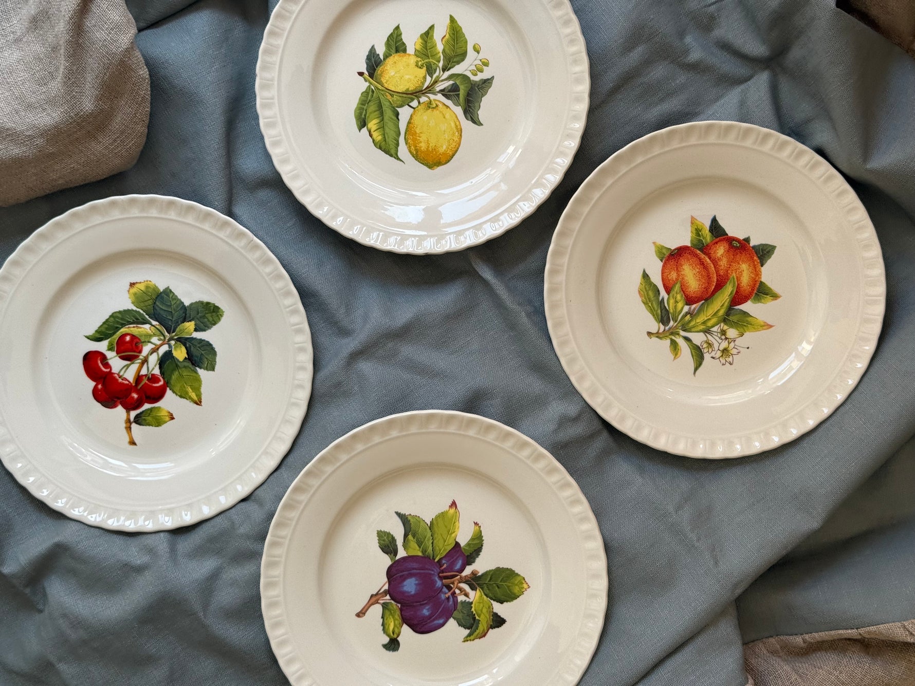 Composizione di piatti vintage decoro frutta assortiti su tessuto elegante
