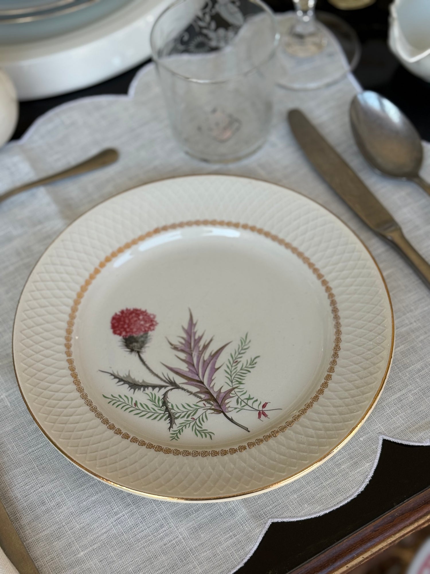 Piatto vintage botanico apparecchiato su tavola elegante con bordo dorato e tovaglietta in lino