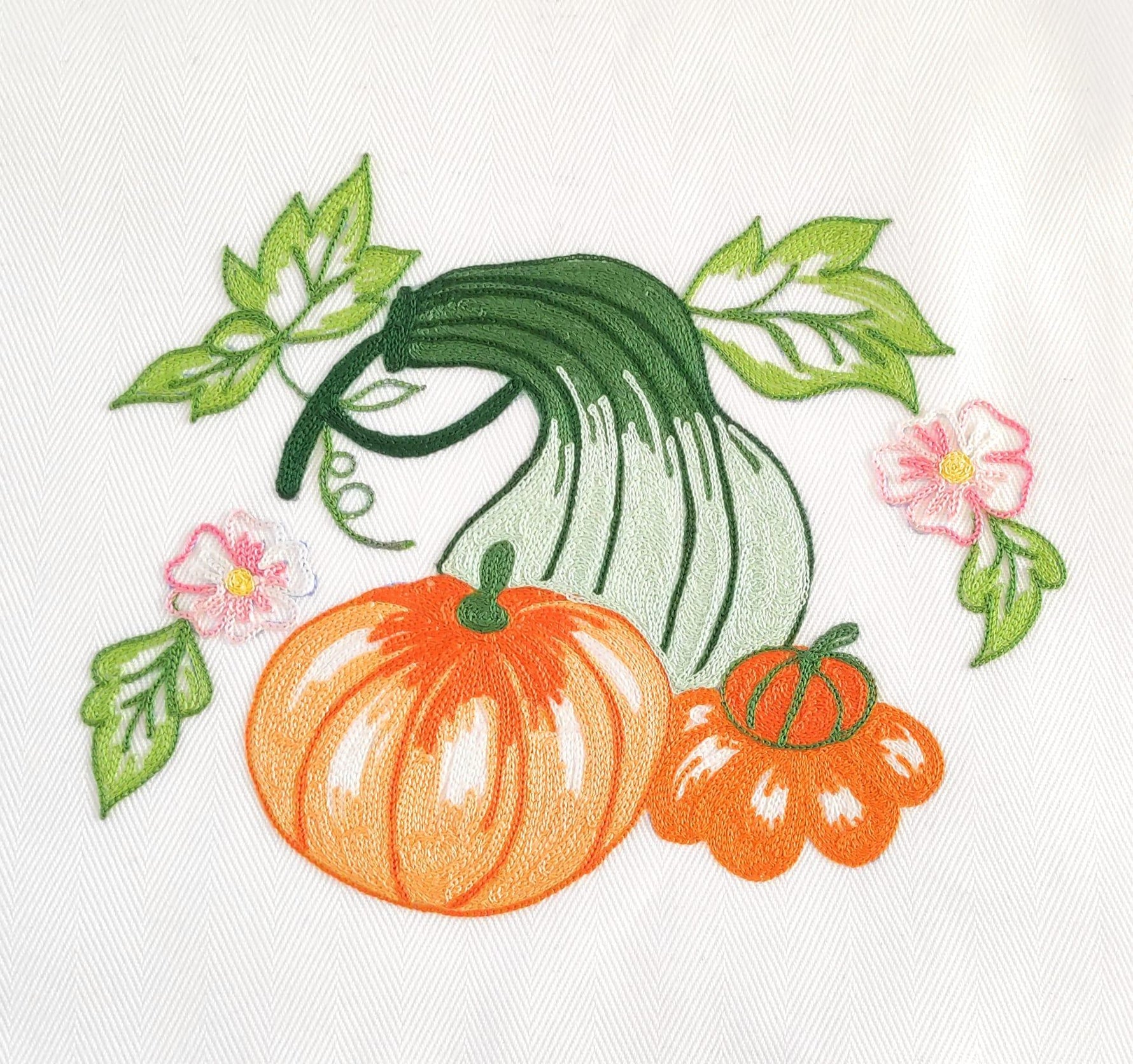 Particolare ricamo con zucche arancio e verdi, foglie verdi e fiori rosa, Made in Italy