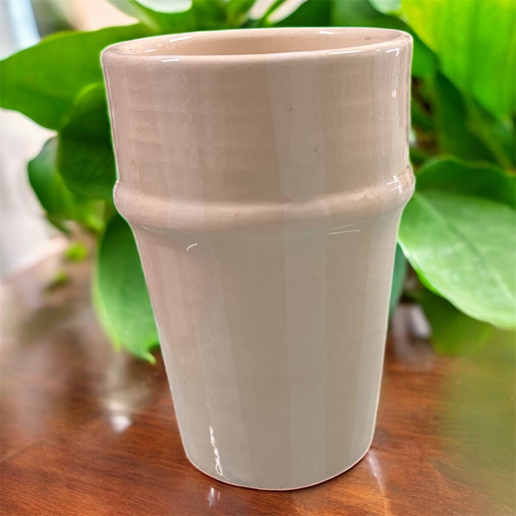 Bicchiere in ceramica artigianale color crema, finitura lucida, design minimal, su superficie in legno