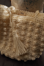 Dettaglio borsa in corda intrecciata con nodi in rilievo e nappa tono su tono, lavorazione artigianale