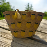 Borsa estiva in paglia con limoni ricamati appoggiata su tavolo in legno, stile mediterraneo Marika Selection
