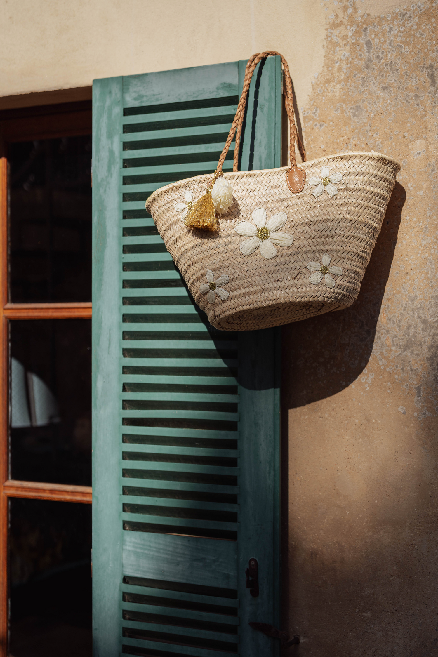 Borsa in paglia intrecciata con fiori ricamati e doppia nappa decorativa appesa a finestra, stile mediterraneo