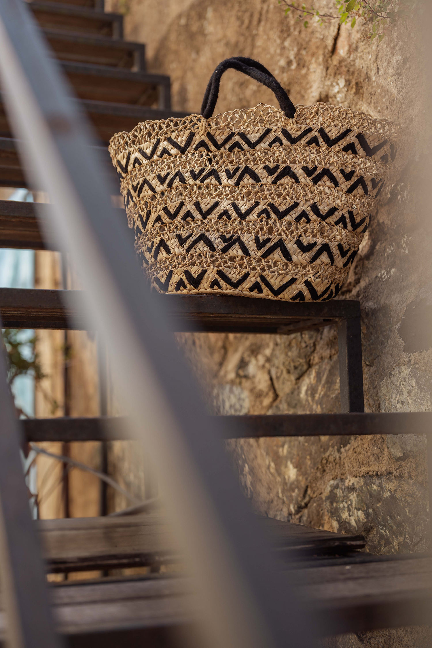 Borsa in paglia naturale con motivo geometrico a contrasto appoggiata su scala, Marika Selection