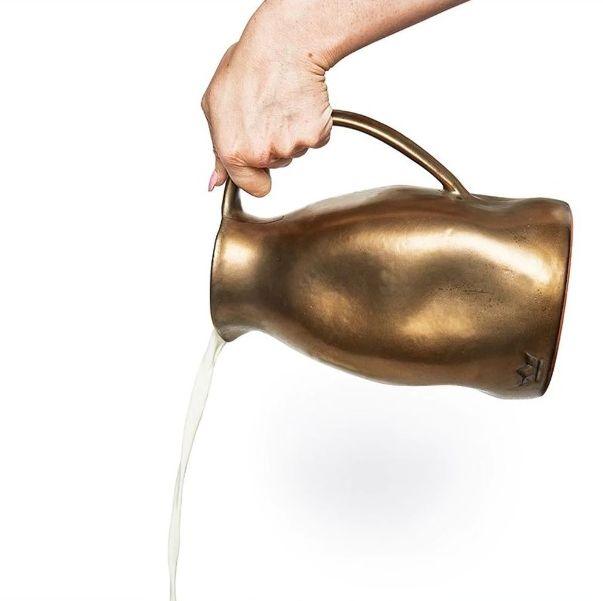 Mano che versa acqua da una caraffa color platino in ceramica smaltata Dutch Deluxes, eleganza artigianale in un gesto quotidiano