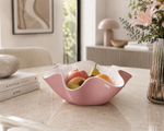 Centrotavola Soft rosa cipria di Vesta Design in cristallo acrilico PMMA con bordo ondulato, ambientato su un elegante tavolo effetto marmo con frutta fresca in un raffinato interno moderno dai toni neutri e luminosi.