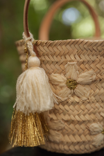 Dettaglio mini borsa in paglia con ricami a margherita e nappina panna e oro