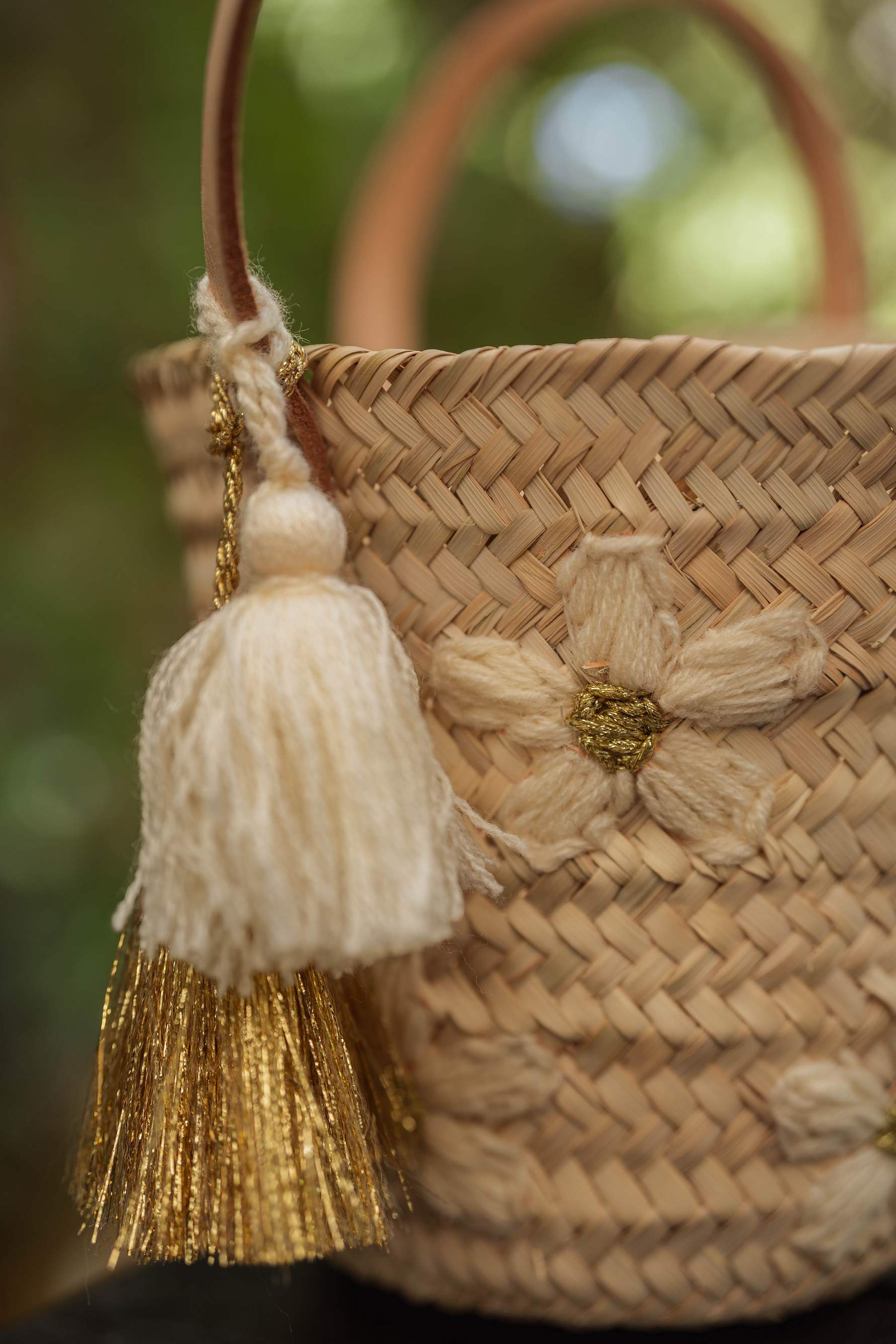 Dettaglio mini borsa in paglia con ricami a margherita e nappina panna e oro