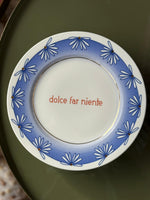 Piatto in porcellana Ø21 cm con scritta Dolce Far Niente e bordo azzurro con fiori blu stilizzati.
