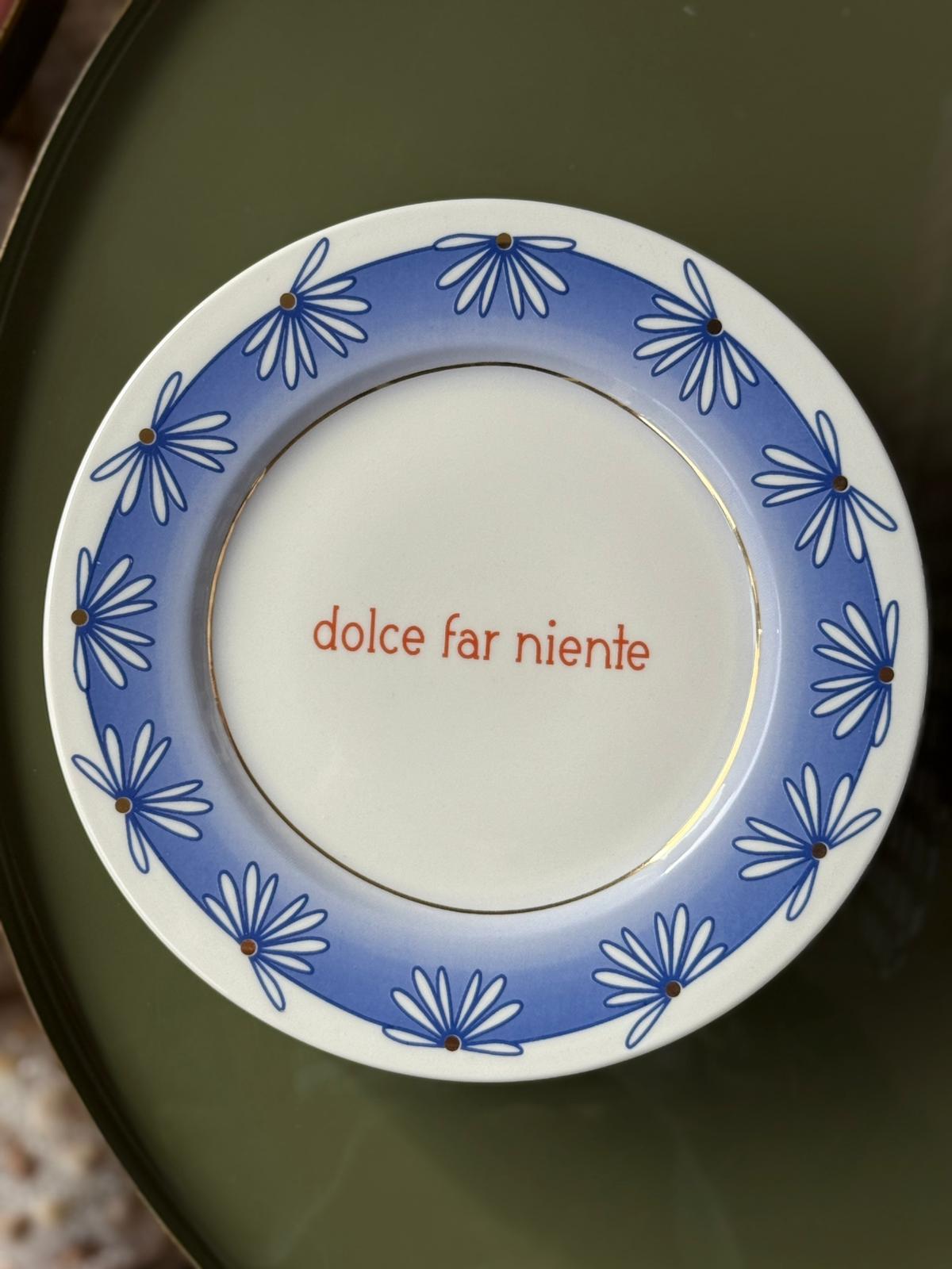 Piatto in porcellana Ø21 cm con scritta Dolce Far Niente e bordo azzurro con fiori blu stilizzati.