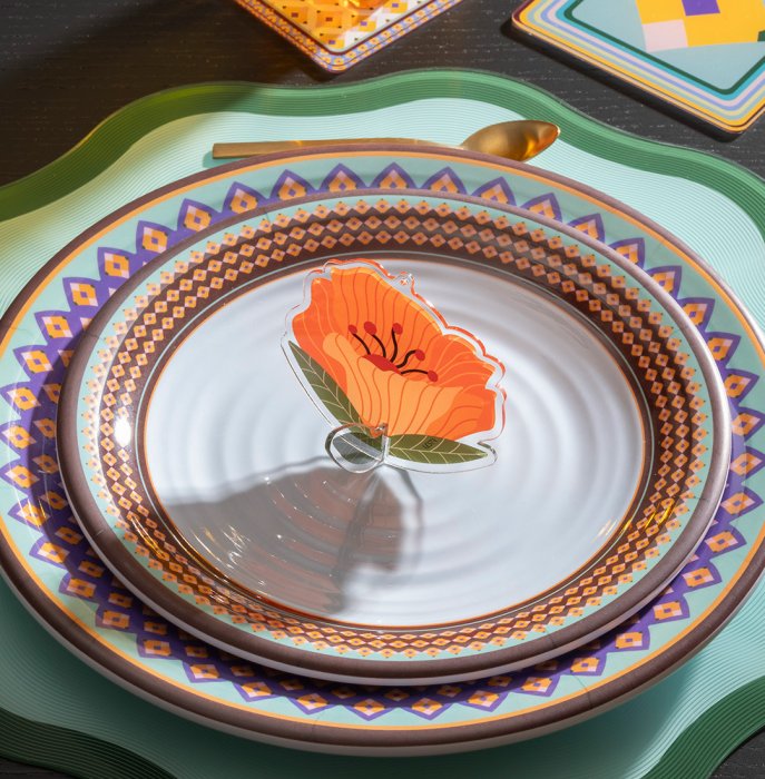 Fiore Funny Flowers di Vesta modello Petunia arancione utilizzato come segnaposto su una tavola apparecchiata con piatti decorati.