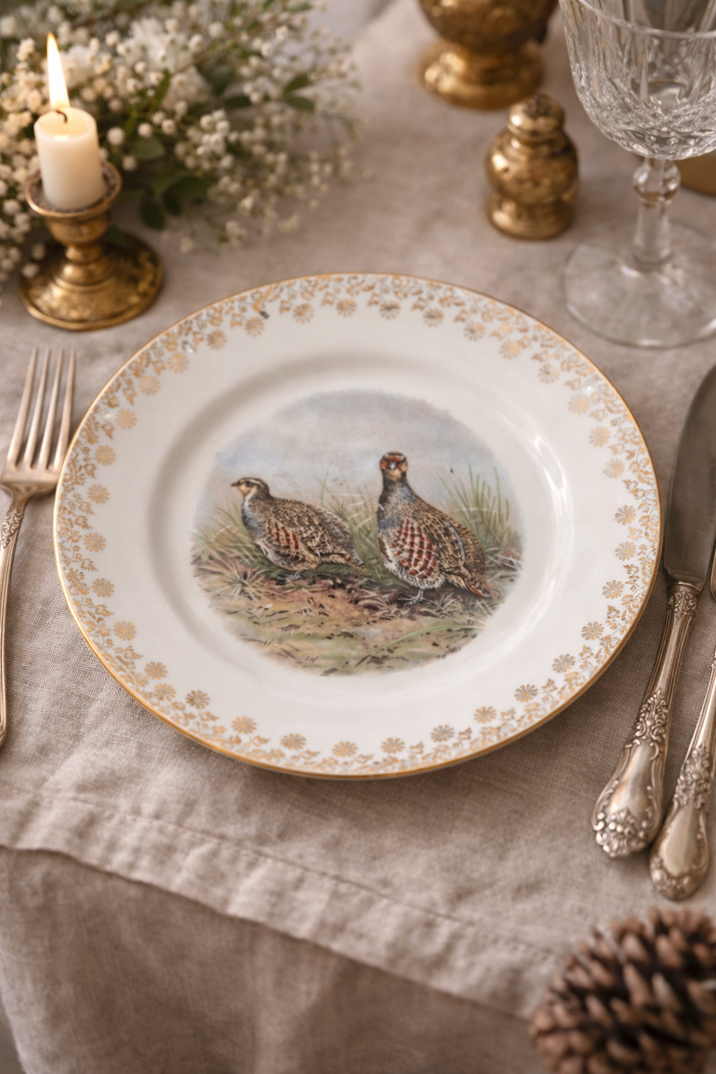 Piatto  vintage Limoges con decorazione di uccelli selvatici, apparecchiato su tavola elegante con lino, posate argentate e luce calda