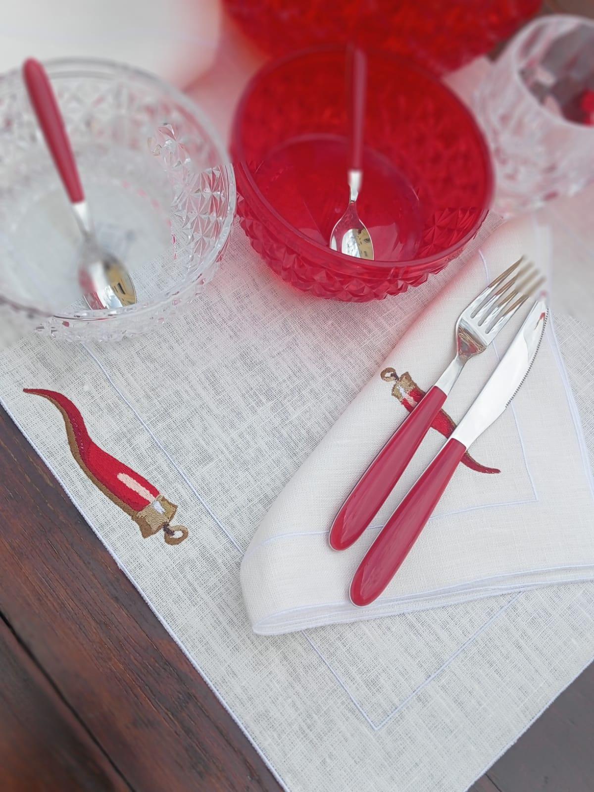 dettaglio elegante del tovagliolo in lino cerato ricamato con corno rosso su tavola estiva, con ciotole acriliche Mario Luca Giusti