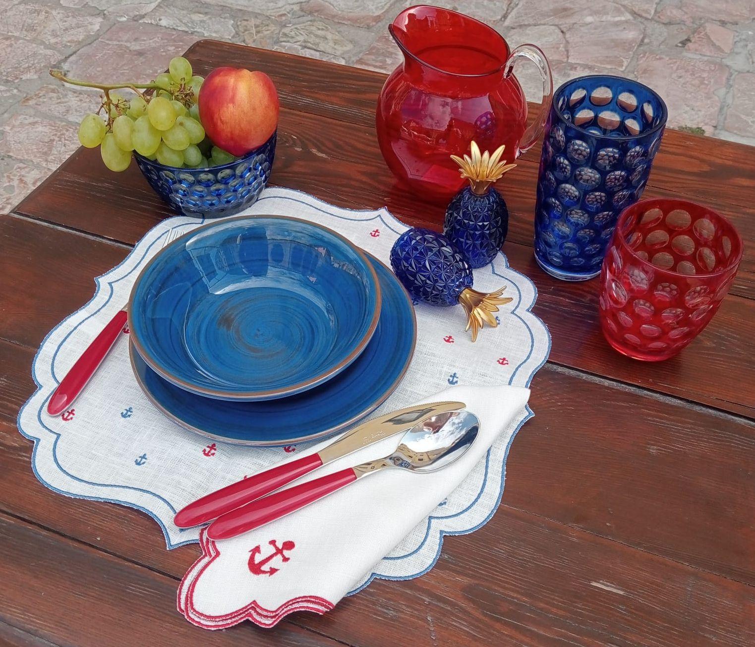 Dettaglio tavola apparecchiata con set lino cerato ricamato con ancore rosse e blu