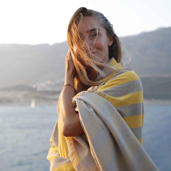  Donna avvolta nel telo MARIS giallo e sabbia su sfondo marino