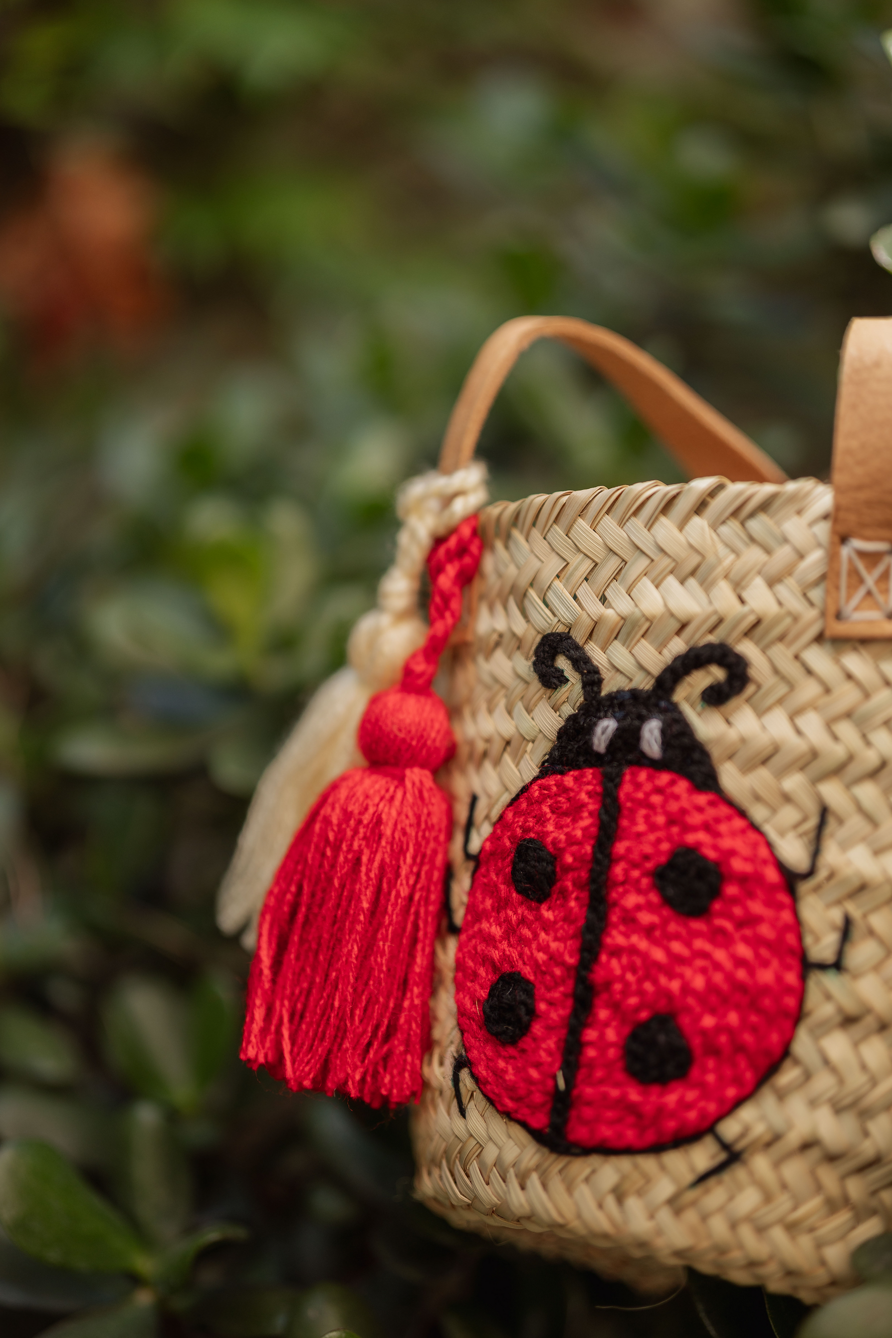 Borsa cestino in paglia con ricamo coccinella rossa e nappine decorative, accessorio estivo fatto a mano