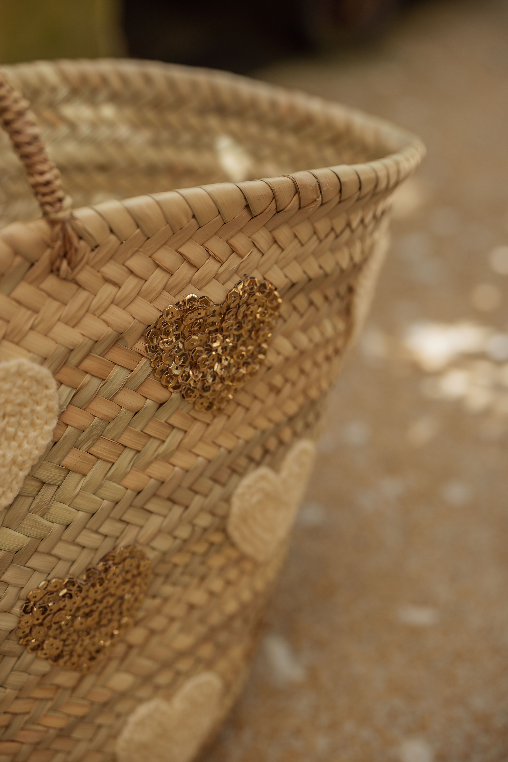 Dettaglio borsa in paglia con cuori ricamati dorati e naturali, lavorazione artigianale