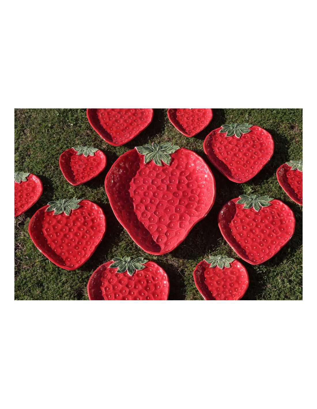 Piatti Fragola Virginia Casa in ceramica rossa con foglie verdi, decorati a mano e disposti su prato, artigianato italiano.