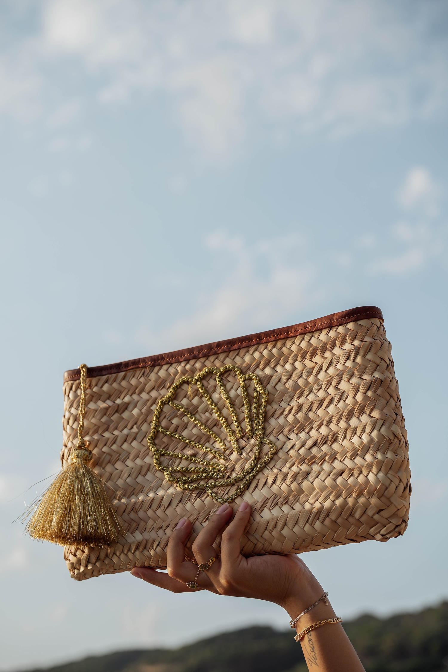 Pochette in paglia naturale con conchiglia ricamata oro e nappa decorativa, accessorio boho chic Marika Selection dallo stile mediterraneo