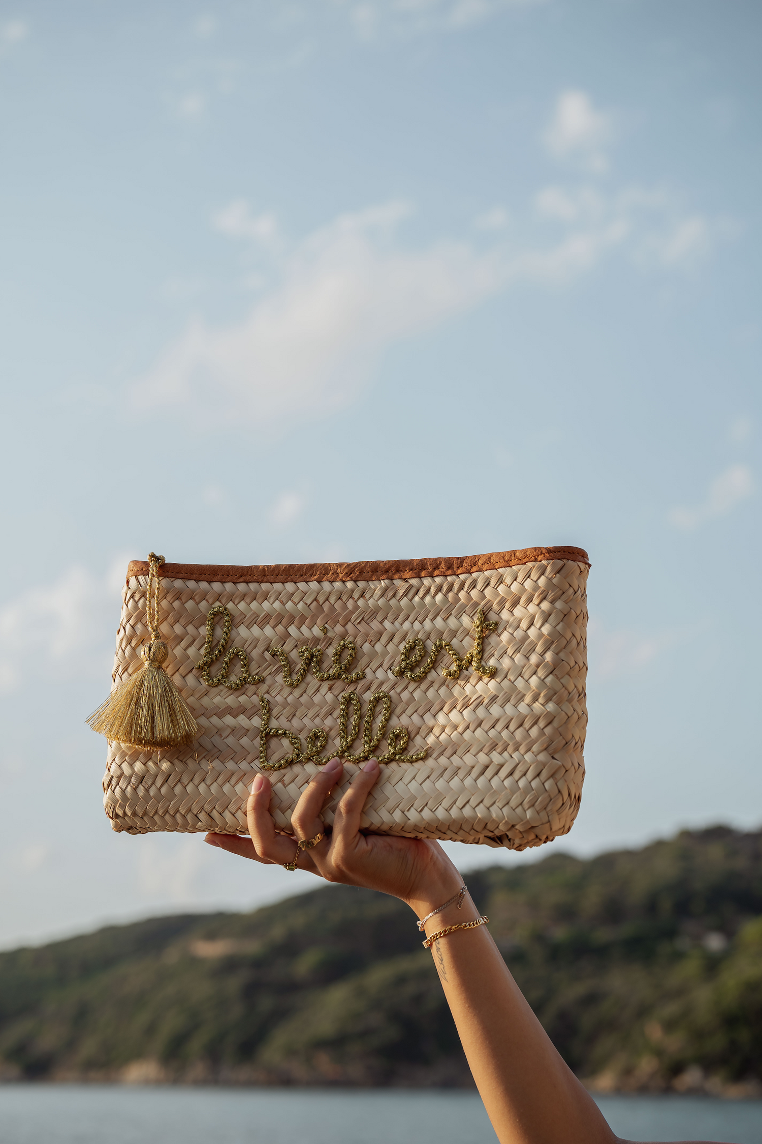 Pochette in paglia naturale con scritta La vie est belle ricamata e nappa dorata, stile mediterraneo estivo