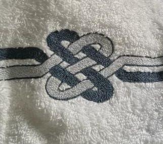 Primo piano sul ricamo nodo marinaro blu su spugna bianca pregiata made in Italy