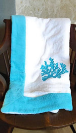 telo mare bianco con ricamo corallo azzurro e bordo azzurro su sedia vintage