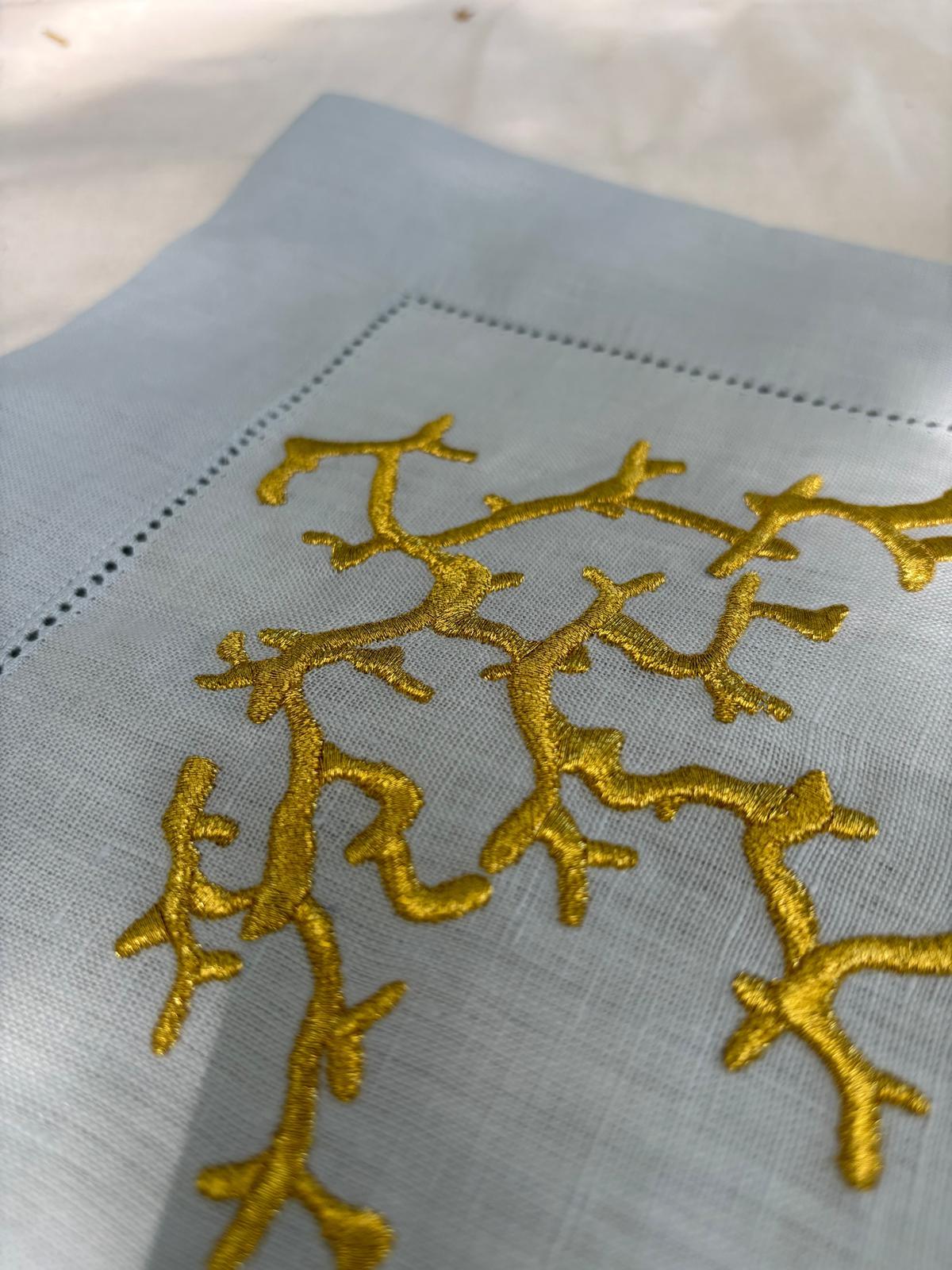 Primo piano del ricamo corallo oro su americano in lino azzurro