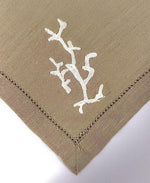 Primo piano del ricamo corallo bianco su tovagliolo in lino beige