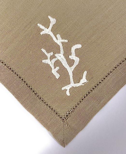 Primo piano del ricamo corallo bianco su tovagliolo in lino beige