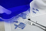 Americano in lino ricamato con pesci blu, con tovagliolo coordinato e mise en place elegante