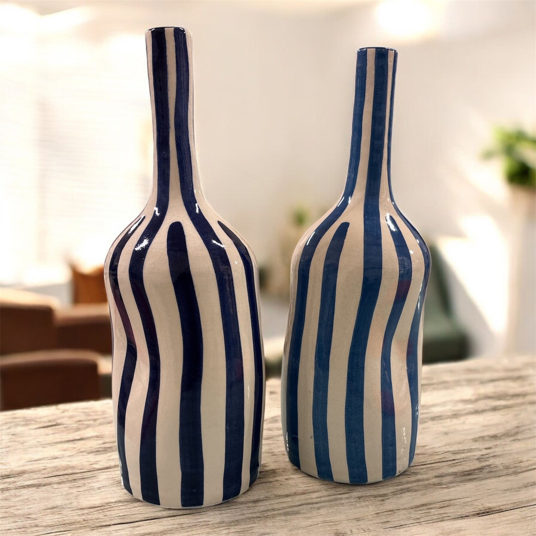 Coppia di vasi in ceramica a righe verticali, nelle varianti bianco e blu e bianco e azzurro, fotografati insieme su superficie chiara.