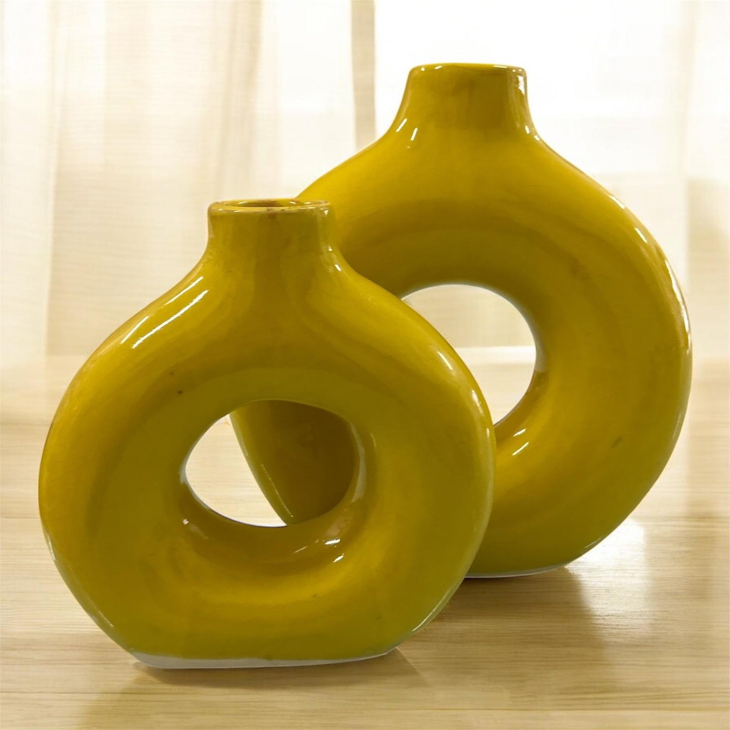 Coppia di vasi gialli in ceramica lucida, grande e piccolo, ambientati su superficie in legno.