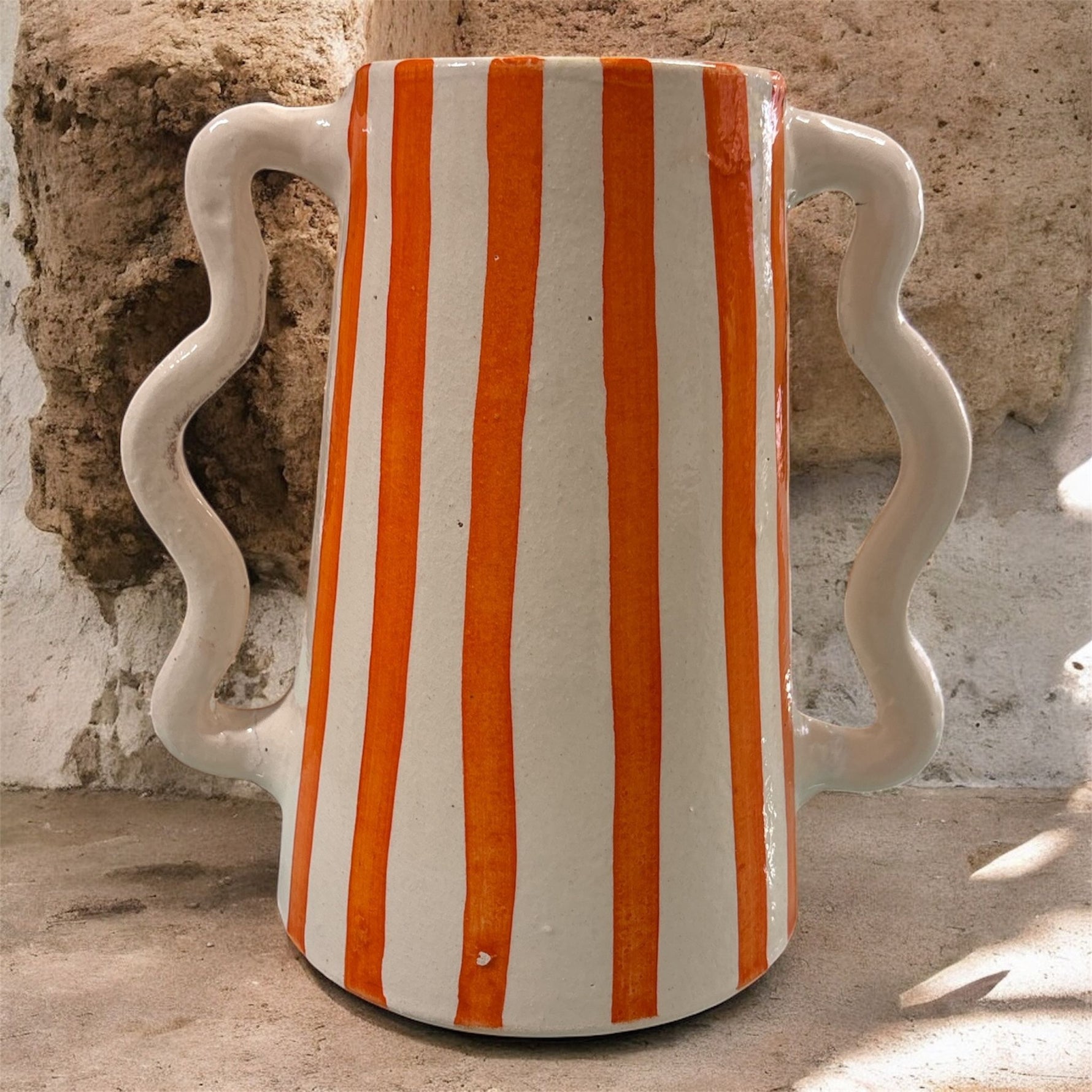 Brocca in ceramica artigianale con righe verticali arancioni e doppio manico ondulato, stile mediterraneo