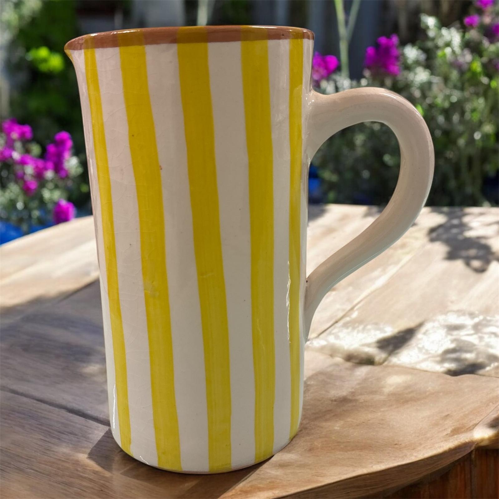 Vaso artigianale in ceramica a righe gialle e terracotta con un manico, fatto a mano, stile solare, ambientato all’aperto