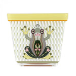 Vasetto JOY in acrilico con decorazione a rana colorata su sfondo verde, visto frontalmente.