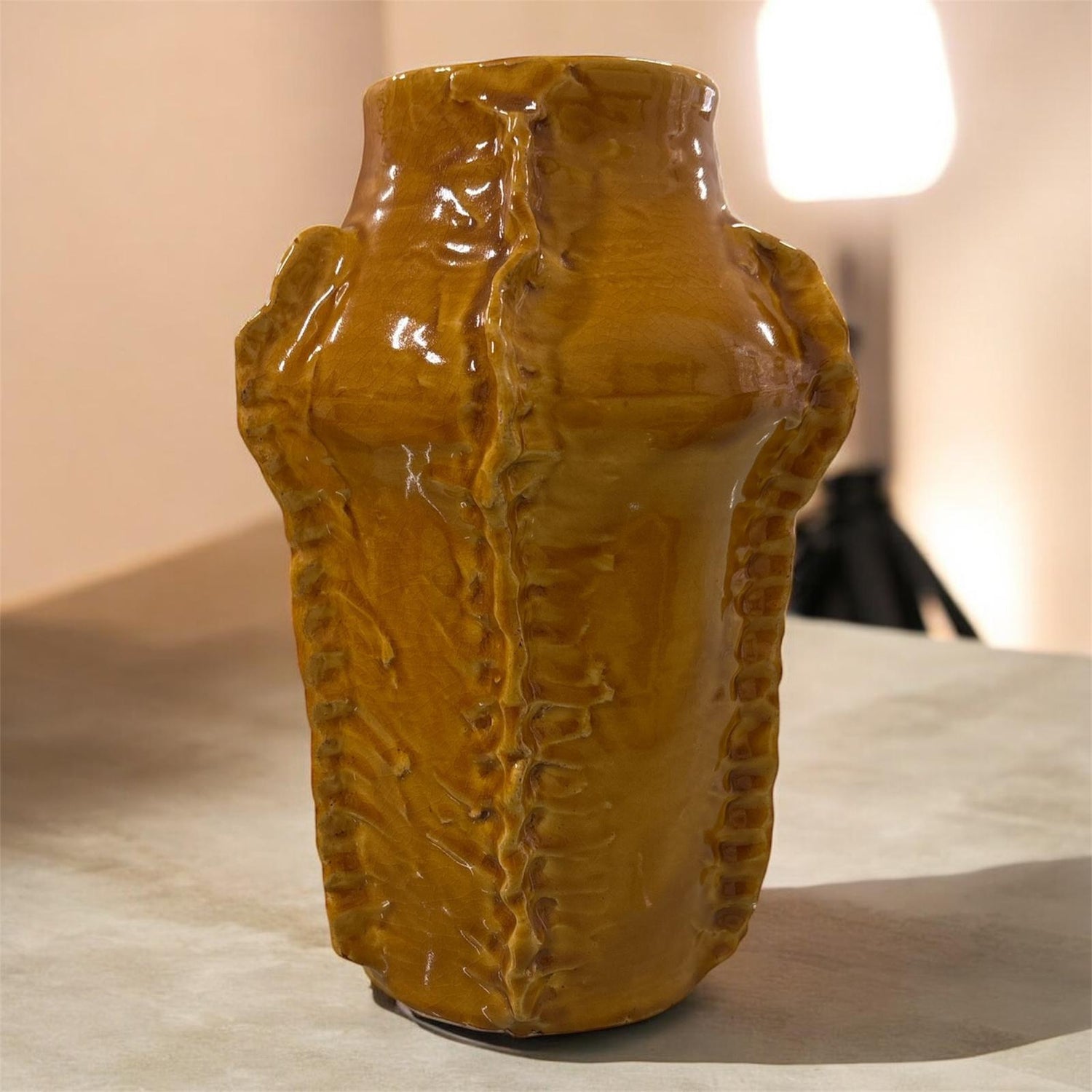 Vaso artigianale color mattone con texture scultorea e finitura lucida, ambientato su piano chiaro.