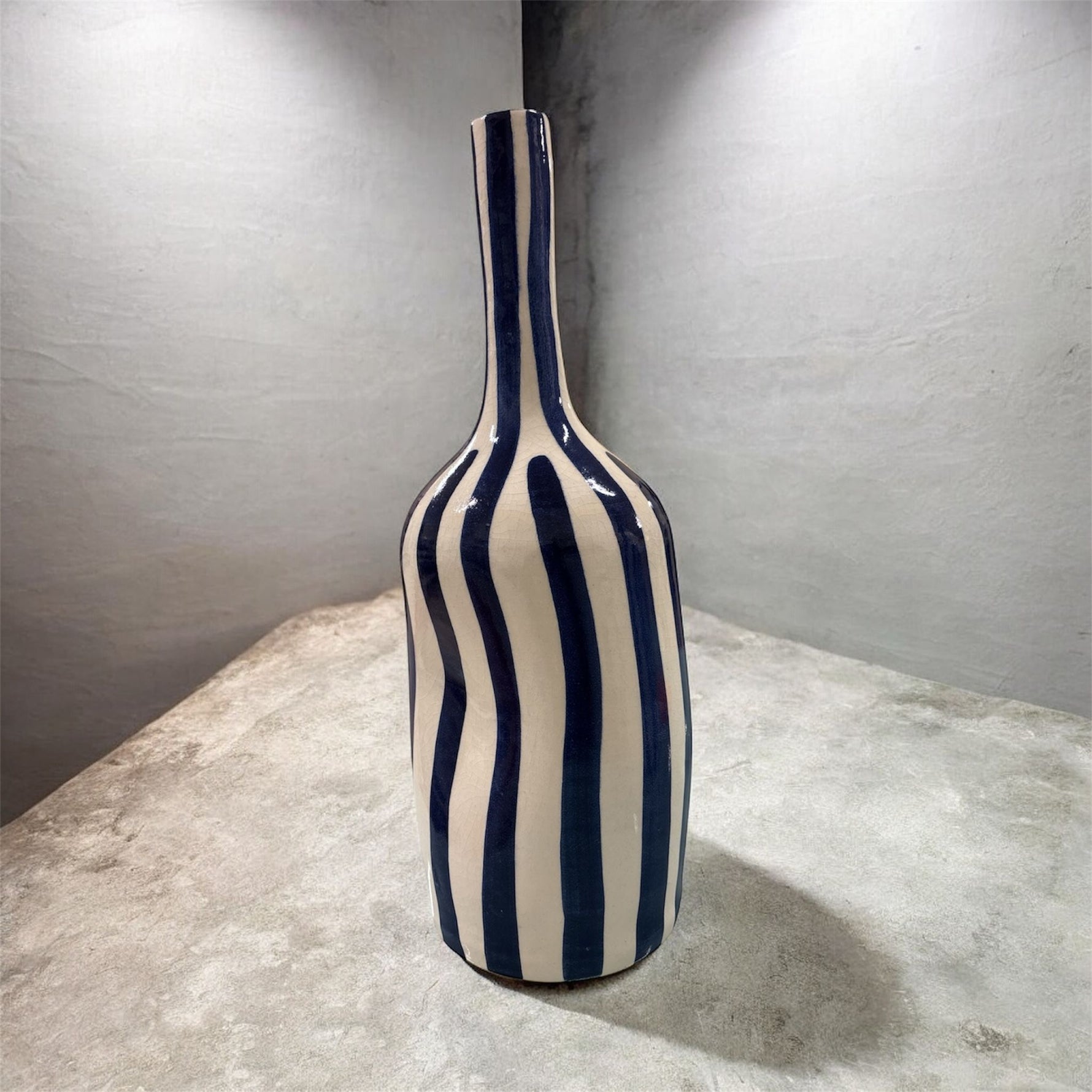 Vaso in ceramica bianco e blu a righe verticali, fotografato su sfondo grigio minimal.